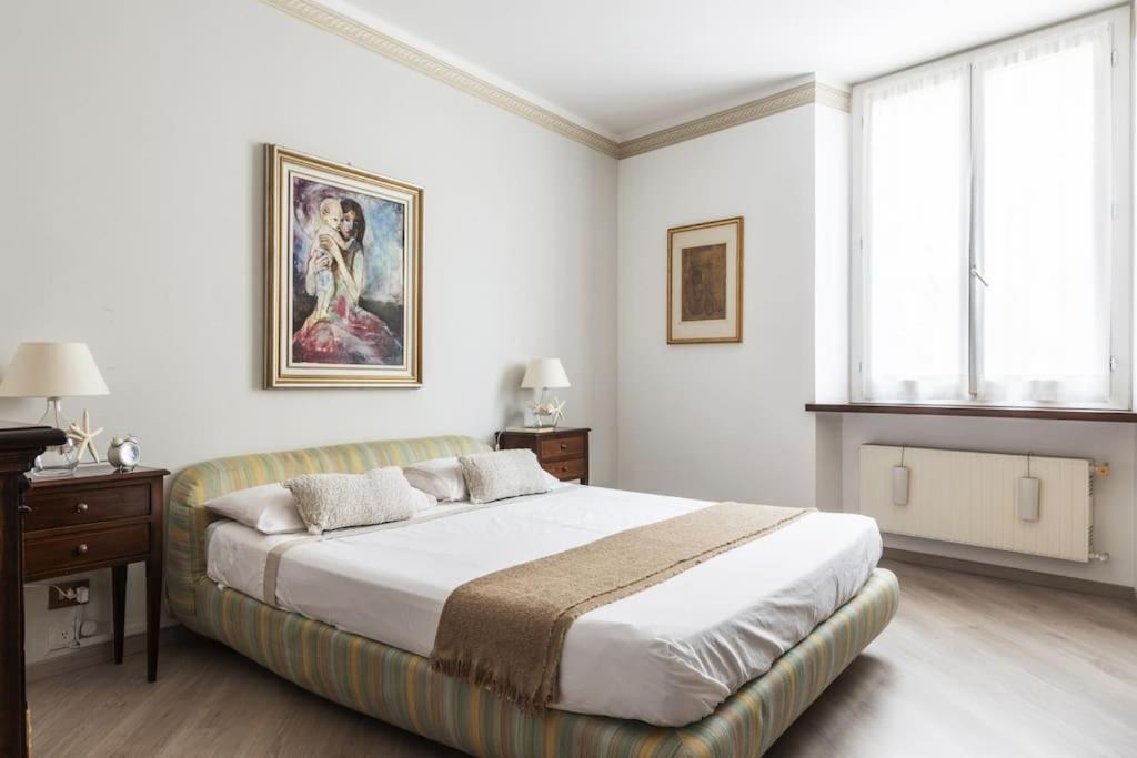 a white bedroom with a large bed and a window at Caprera Flexyrent NO air conditioning - Seafront in Santa Margherita Ligure