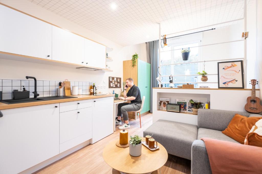 a man sitting in a kitchen in a living room at Résidence Kley Angers in Angers