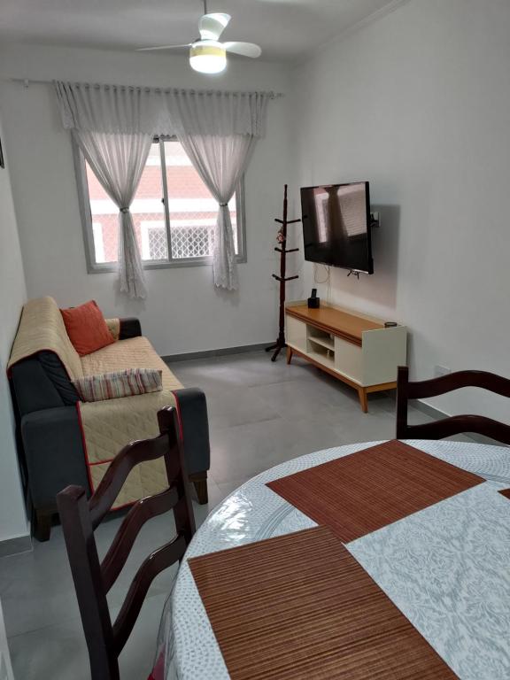 a living room with two beds and a tv at Apartamento Pé na Areia - Praia Grande - SP, Aviação in Praia Grande