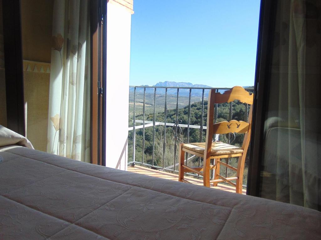a bedroom with a bed and a chair on a balcony at Hotel Sierra de Araceli Lucena in Lucena