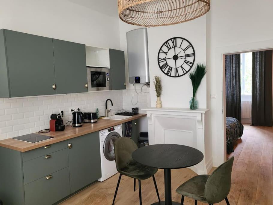 eine Küche mit einem Tisch und Stühlen sowie einer Uhr an der Wand in der Unterkunft Appartement moderne calme et spacieux-Centre Thuillat in Limoges