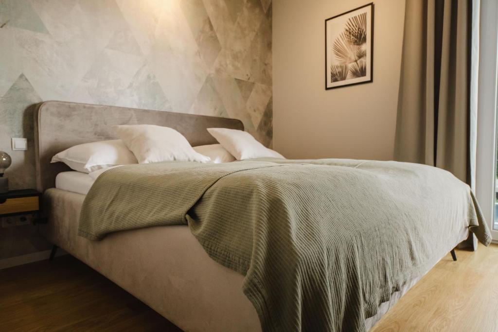 ein Bett mit einer grünen Decke und weißen Kissen in der Unterkunft URBAN UNIT - nearby city center in Wien