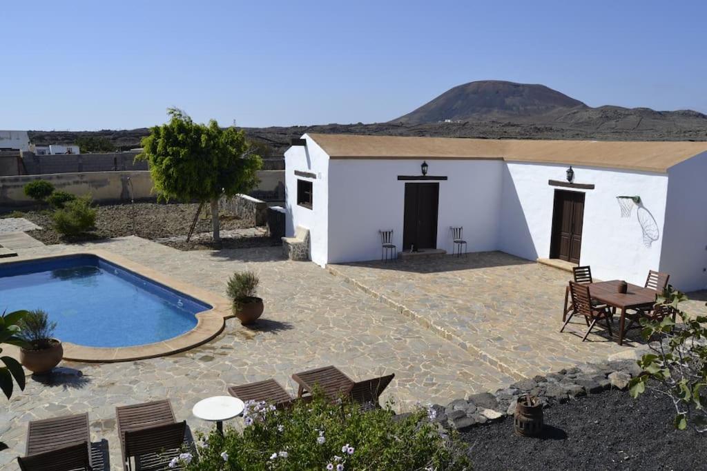 a villa with a swimming pool and a table and chairs at Casa Volcán in La Oliva