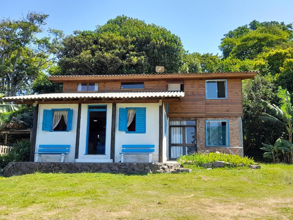 uma pequena casa com portas azuis num campo em Refúgio da Mata Atlântica Sobrado Centenário em Torres