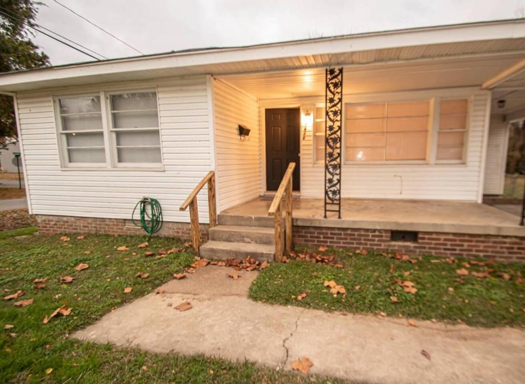 une maison blanche avec une véranda et une véranda dans l'établissement Home Sweet Home Bungalow, à North Little Rock