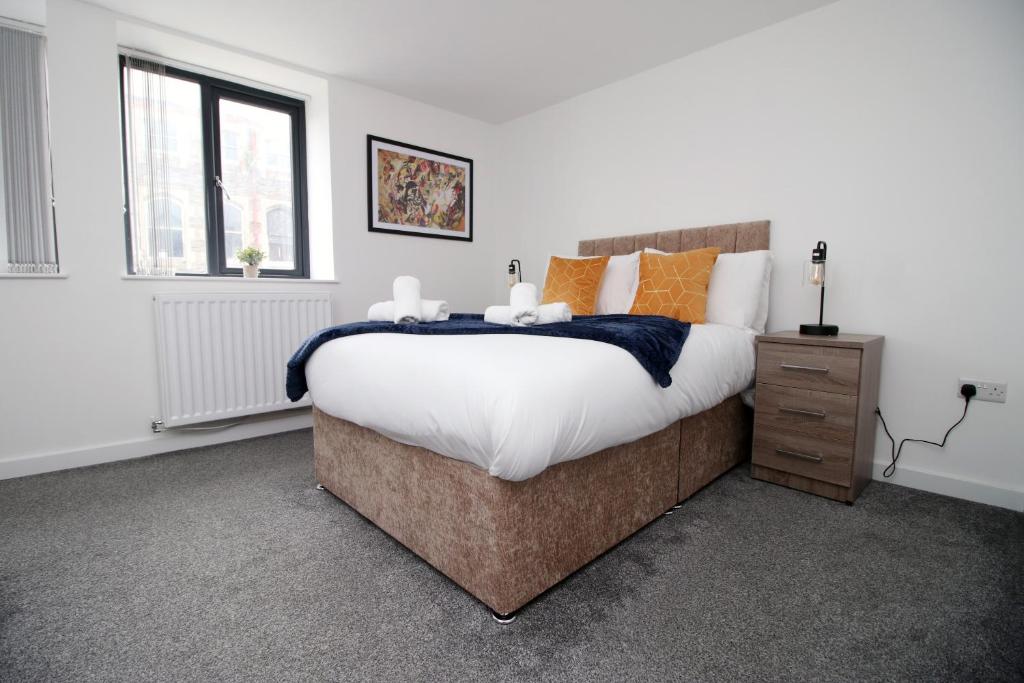 a bedroom with a large bed with white and orange pillows at Luxury City Loft Apartment! Great Location in Cardiff