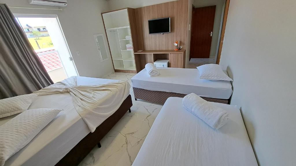 a hotel room with two beds and a television at Pousada Valentina in Penha