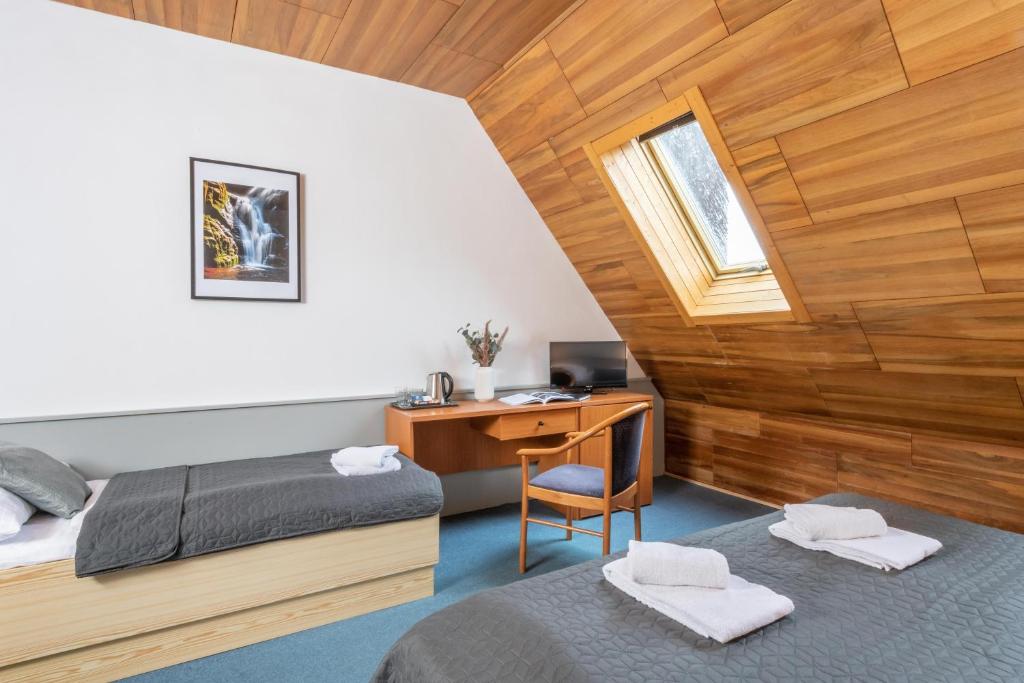 a bedroom with two beds and a desk and a window at Wellness Hotel Šedý Vlk in Harrachov