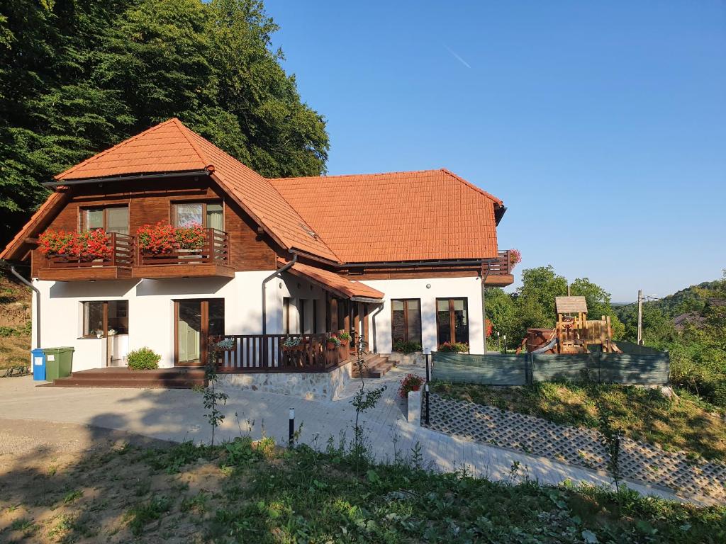 a white house with a brown roof at Pensiunea Nossa Panzió in Corunca