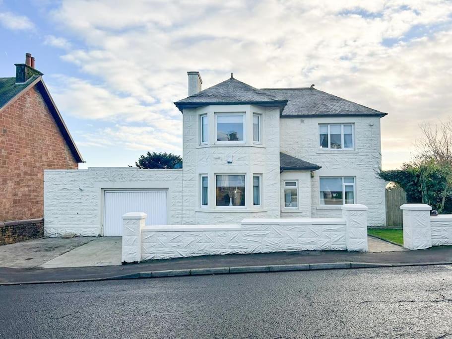 a white house with a white fence in front of it at The Old High Road in Stevenston