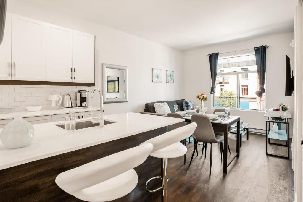 a kitchen and living room with white cabinets and a table at M11 Luxury 1BR Sofa Bed in the heart of PlateauMile-End in Montreal