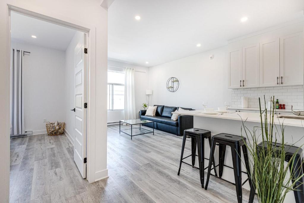 a white kitchen and living room with a blue couch at M11 Upscale Spacious 1BR wKingBed AC in Heart of PlateauMile-End in Montréal