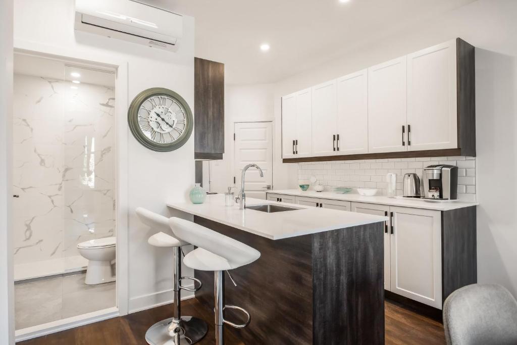 a kitchen with white cabinets and a sink and a clock at M11Upscale 1BR Sofabed in heart PlateauMile-end in Montréal
