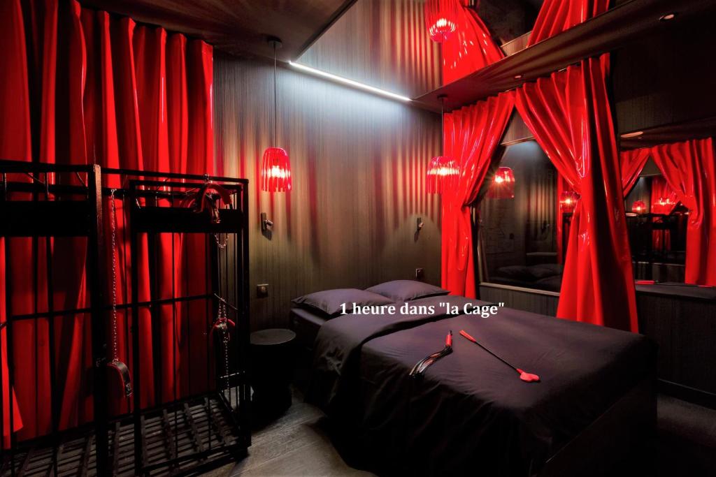 a bedroom with red curtains and a bed with a mirror at Love Hôtel avec nuit insolite au Dandy et Jacuzzi privatisé in Paris