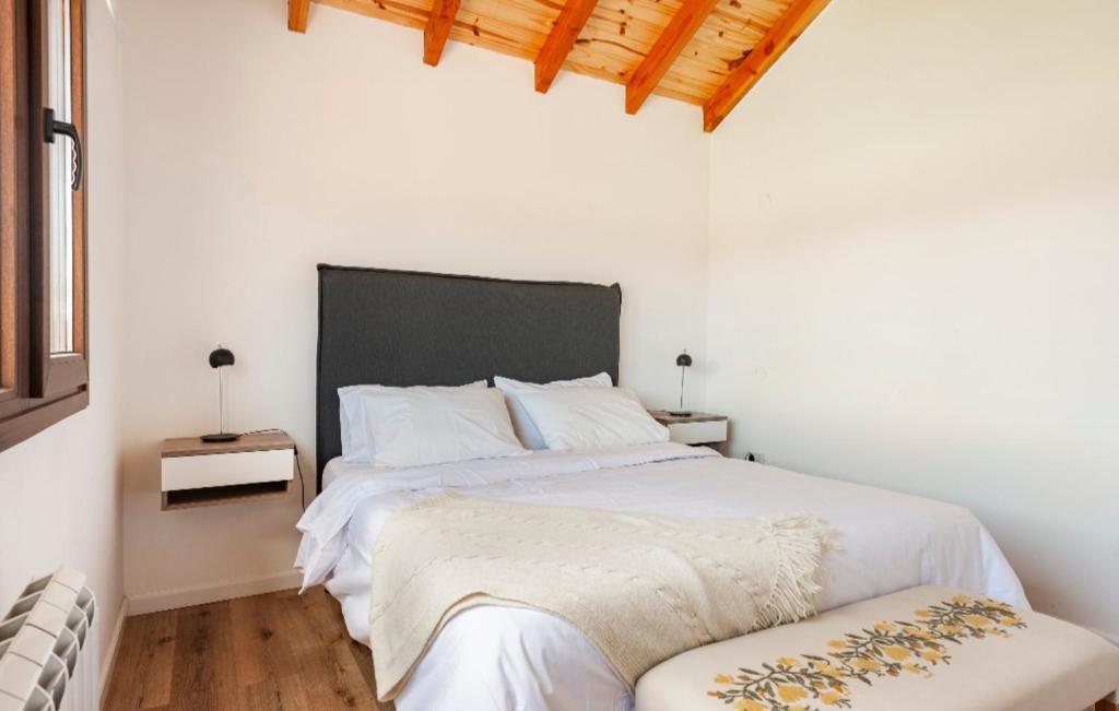 a bedroom with a large white bed with a black headboard at Jardín de Estepa in Dina Huapi