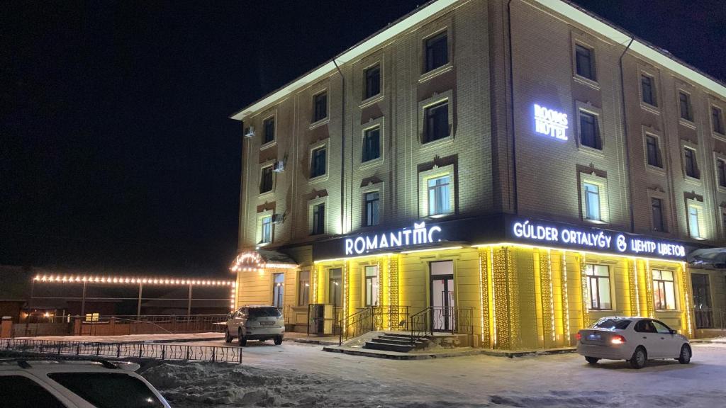 Rooms Hotel Semey في سيمي: مبنى كبير بواجهة صفراء بالليل