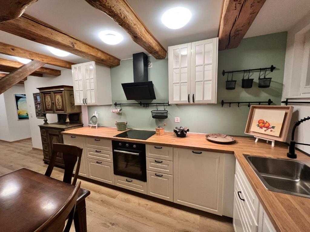 a kitchen with white cabinets and a sink and a table at Idyllischer Bauernhof mit Charme in Benken