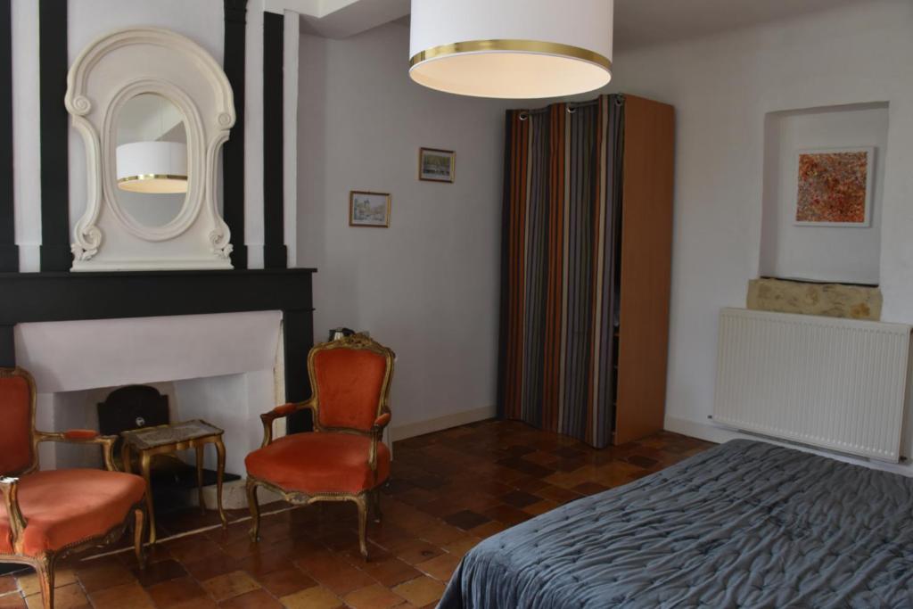 - une chambre avec un lit, deux chaises et une cheminée dans l'établissement Chambres d'hôtes - Dîners - Piscine - centre-ville Bergerac 5km - Domaine de Bellevue Cottage, à Lembras