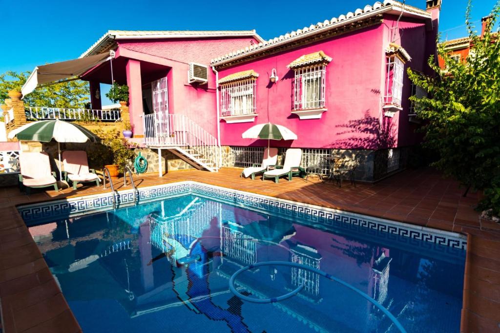 una piscina frente a una casa rosa en La Casita de Gracia, en Monachil