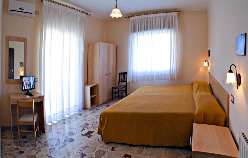 una camera d'albergo con letto, scrivania e finestre di Villa Santantonio a Giardini Naxos