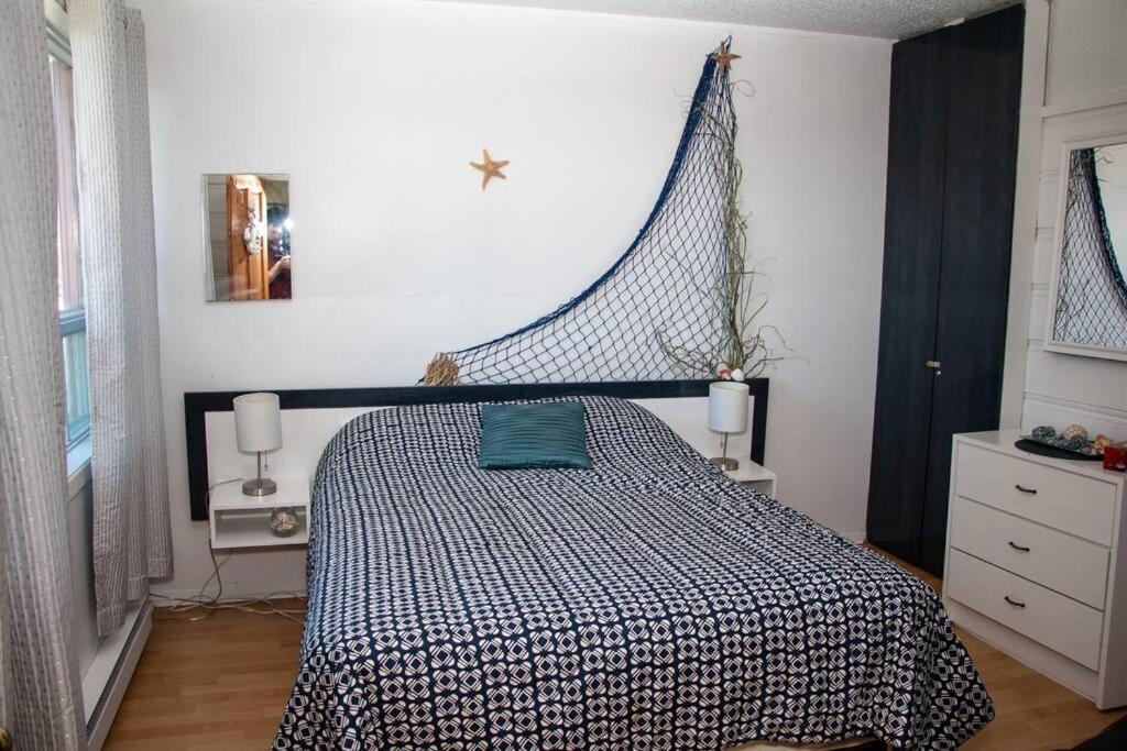 Schlafzimmer mit einem Bett mit einer schwarzen und weißen Bettdecke in der Unterkunft Corail de mer 4 à 2 min de la plage in Sainte-Luce-sur-Mer