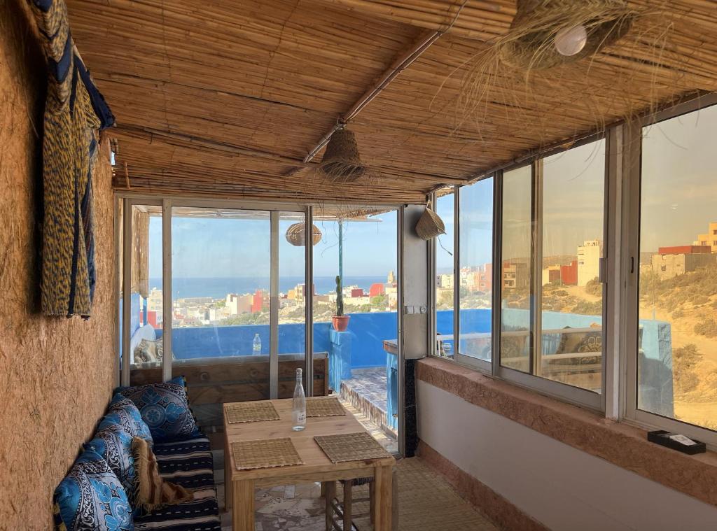 een kamer met een tafel en een aantal ramen bij Let Us Surf in Agadir