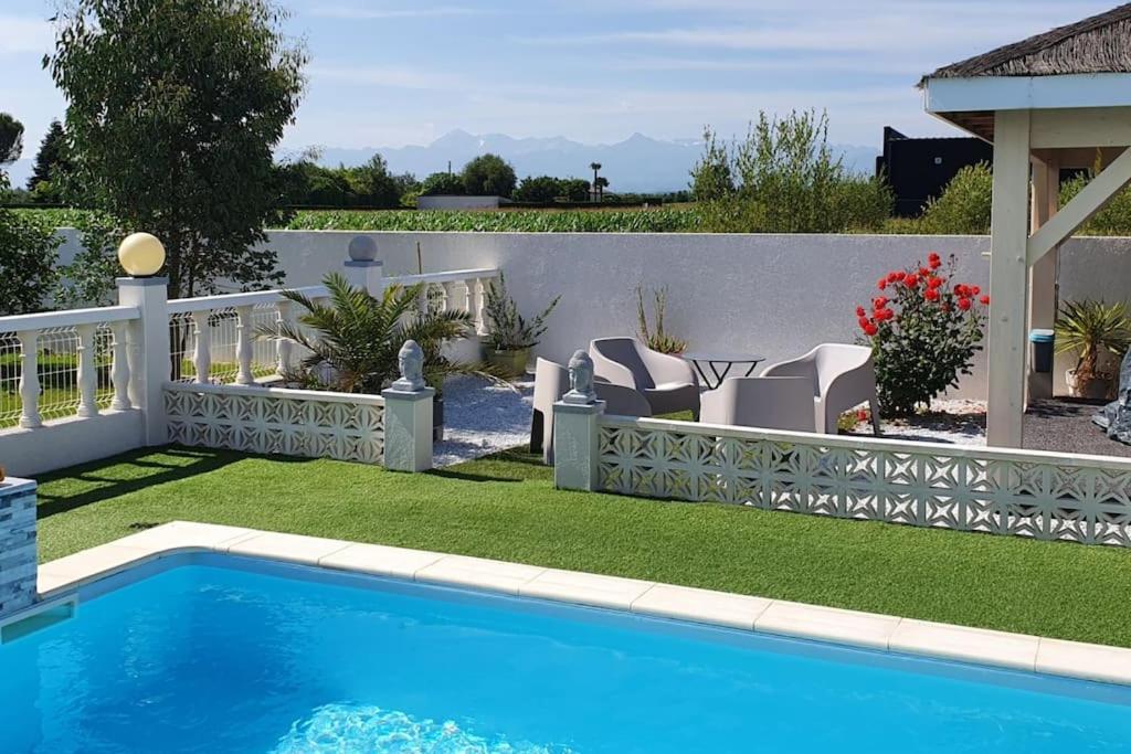 un patio trasero con piscina y una valla blanca en GITE Appartement 2/3 pers., en Bordères-sur-lʼÉchez