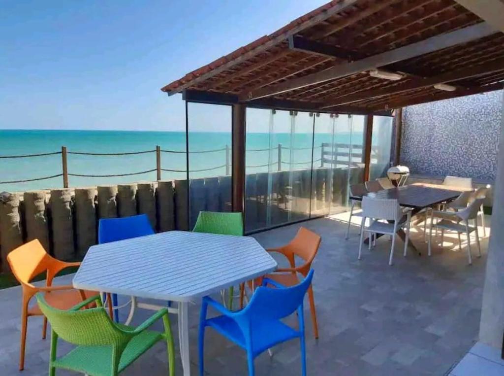 a patio with tables and chairs and the ocean at Paraíso Pé na Areia em Maragogi in Maragogi