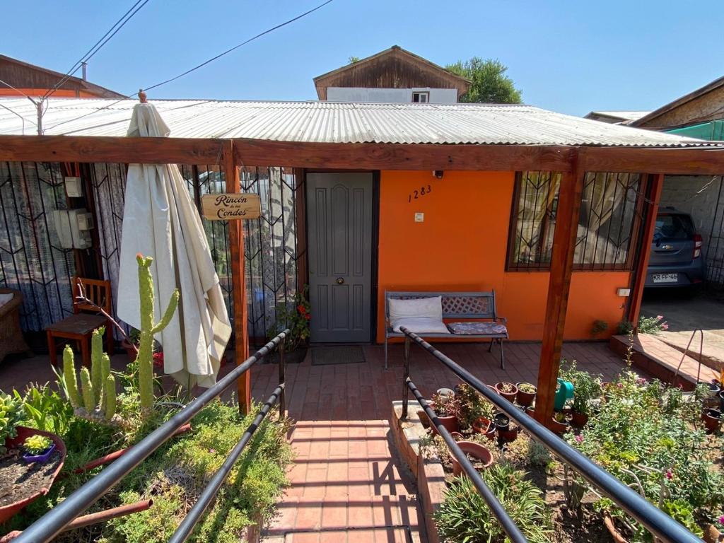 Casa de color naranja con porche y patio en Rincon de Las Condes, en Santiago