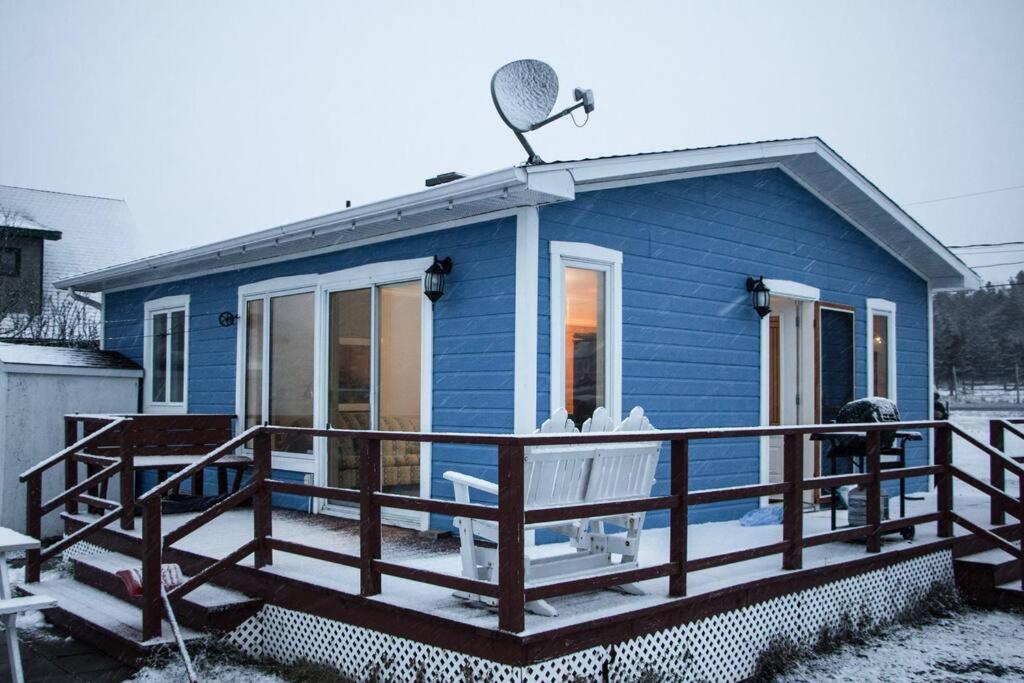a blue tiny house with a large deck at Chalet Le Marin à 5 minutes du centre ville in Sainte-Flavie