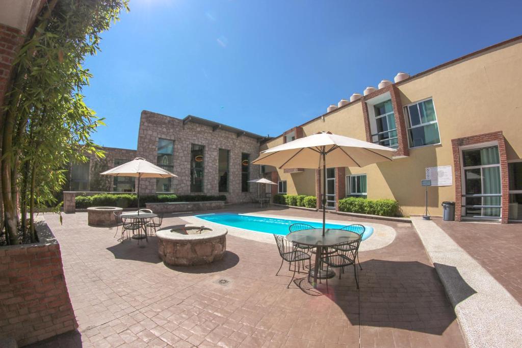 a patio with a pool and tables and chairs and umbrellas at Hotel Camino de Piedra in Guanajuato