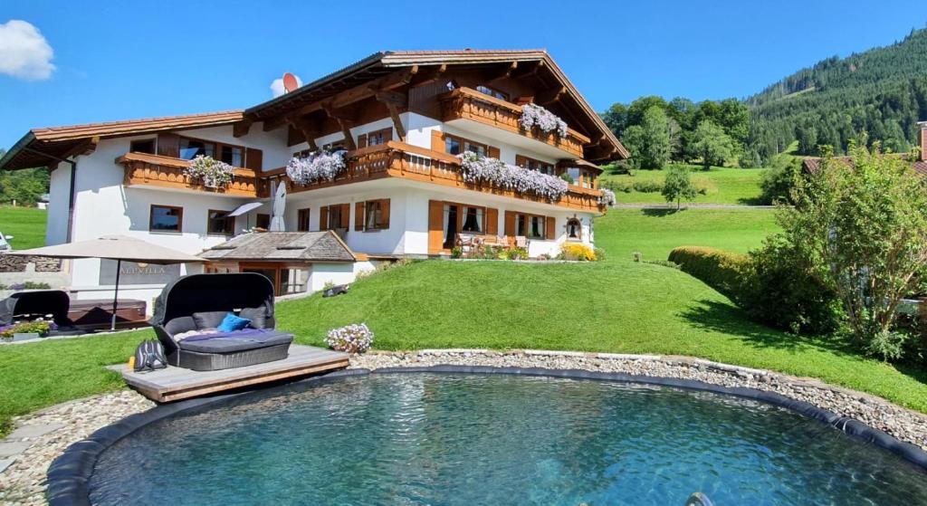 a house with a large swimming pool in front of it at Alpvilla Bietsch in Oberstdorf