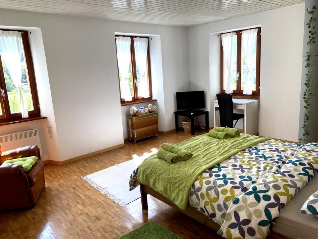 Schlafzimmer mit einem Bett, einem Schreibtisch und Fenstern in der Unterkunft in lak'ech - rooms in Chironico