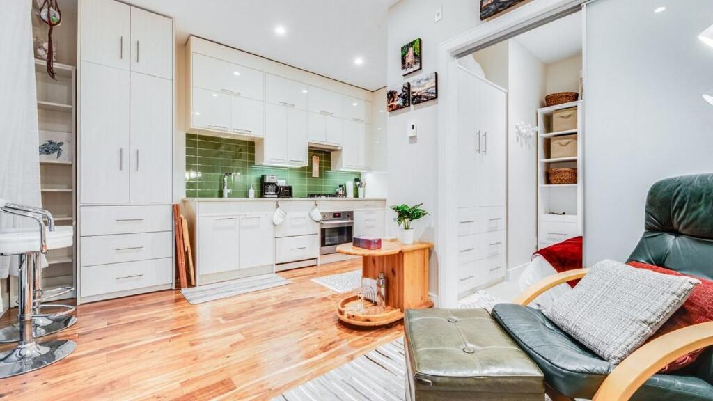 una cucina con armadi bianchi e un divano verde di City Side Near Cook Street Village a Victoria