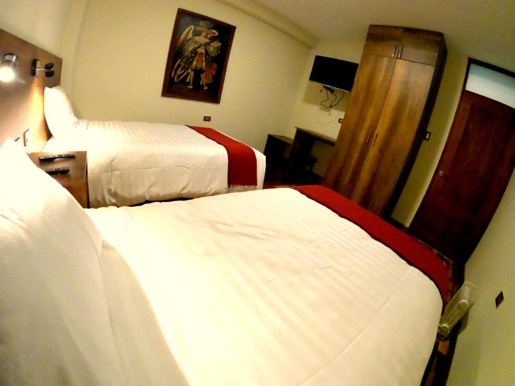 a hotel room with two beds and a mirror at Zans Apartments Cusco in Cusco