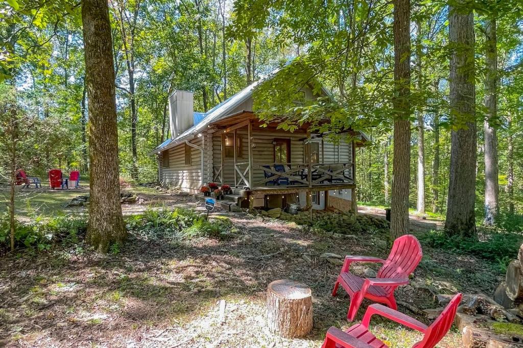 una cabaña en el bosque con sillas rojas y árboles en Cabin and Creek - Secluded Oasis - 3BD, en Kingston Springs