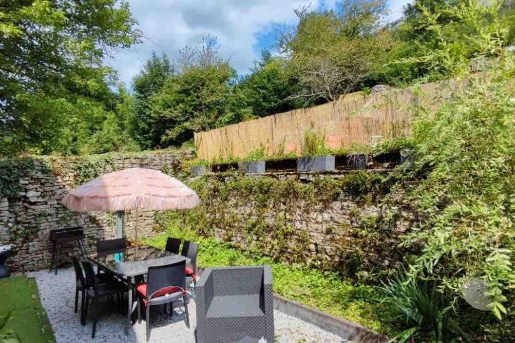 une terrasse avec une table, des chaises et un parasol dans l'établissement Côté Jardin, à Ornans