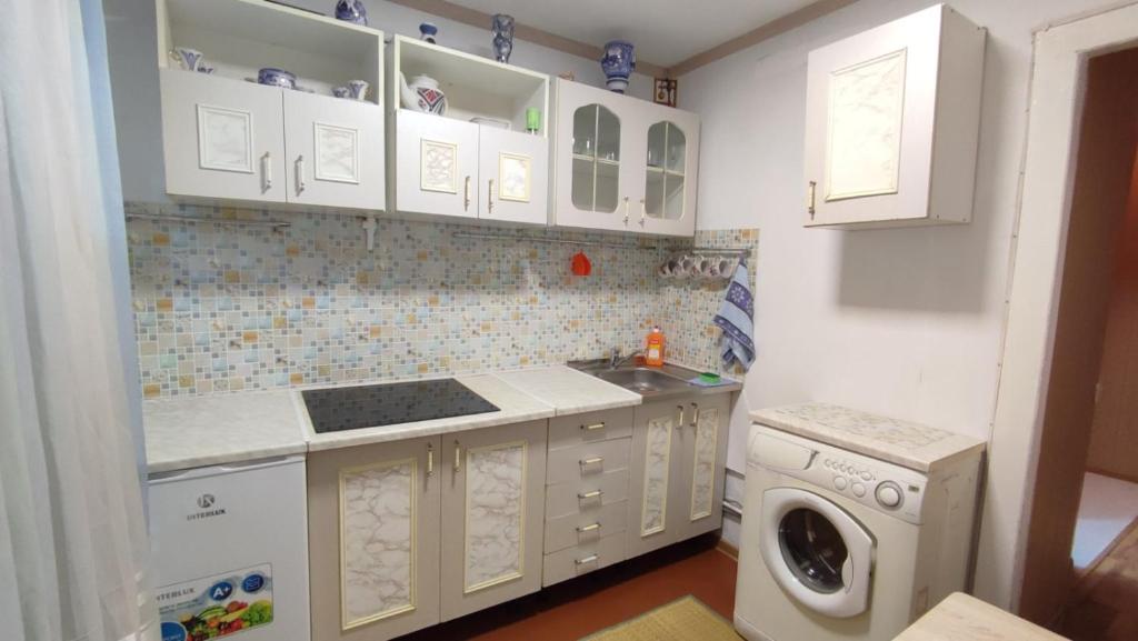 uma cozinha com armários brancos e uma máquina de lavar roupa em Sunday em Chornomorsk