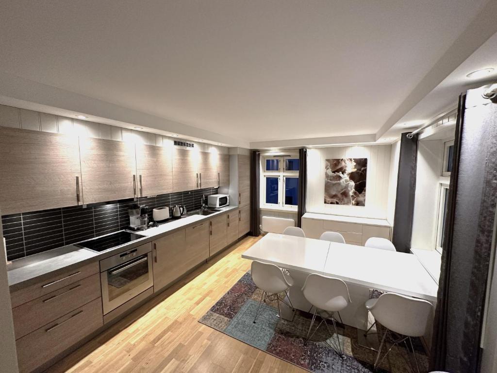 eine große Küche mit einem großen weißen Tisch und Stühlen in der Unterkunft Stetind - Modern apartment with free parking in Narvik