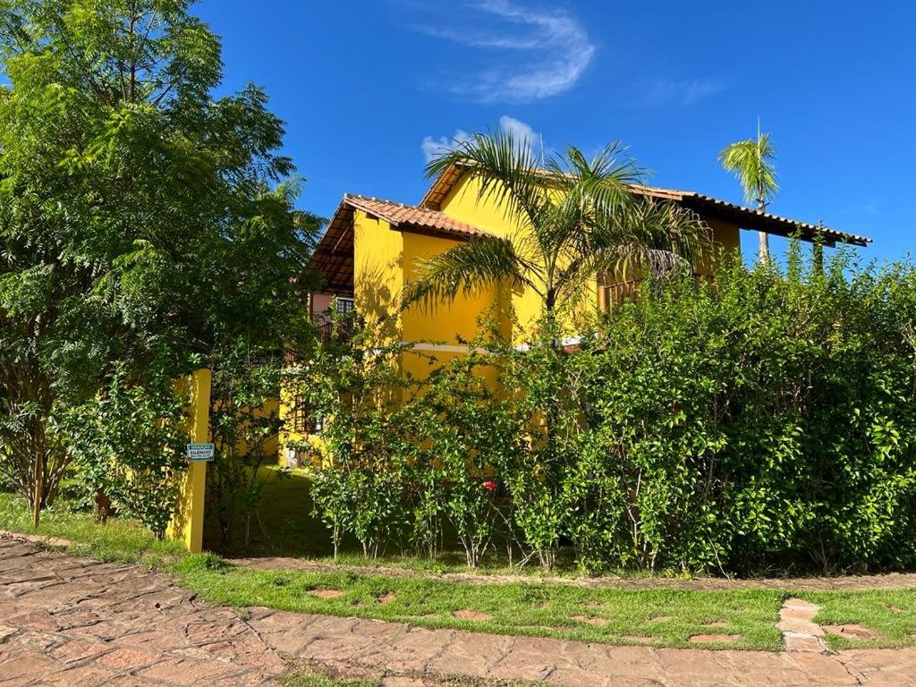 una casa amarilla con palmeras y arbustos en Casa Linda Lençóis, Chapada Diamantina, Bahia, en Lençóis