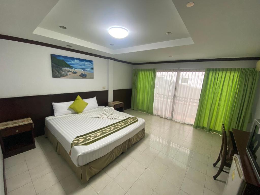 una camera da letto con un grande letto con tende verdi di Sue@Cozy Guesthouse a Kata Beach