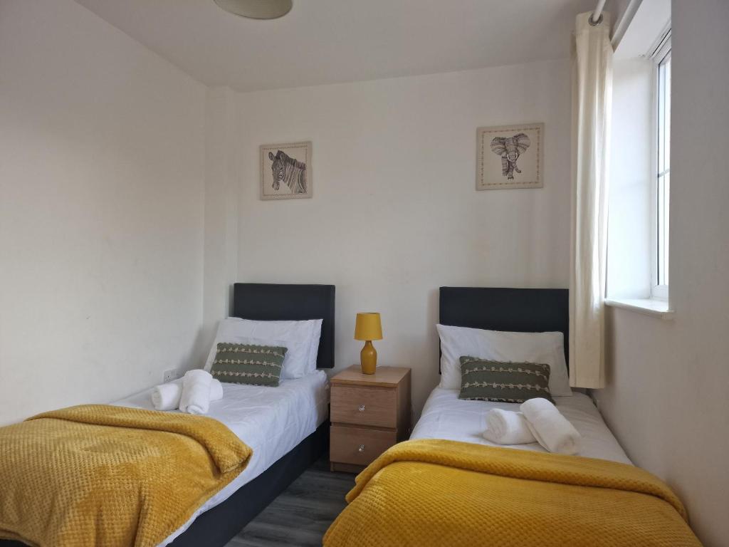 1 dormitorio con 2 camas y ventana en The Commuter's Lodge en Laindon