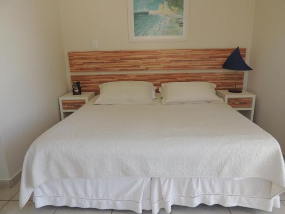 1 dormitorio con 1 cama blanca grande y 2 mesitas de noche en Pousada Ancoradouro's, en Florianópolis