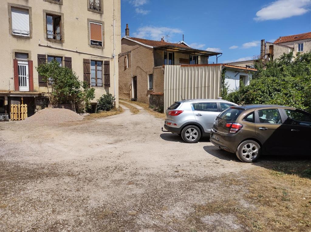 zwei Autos auf einem Parkplatz neben einem Gebäude geparkt in der Unterkunft Les Hortensias studio Rez de chaussée in Bourbonne-les-Bains