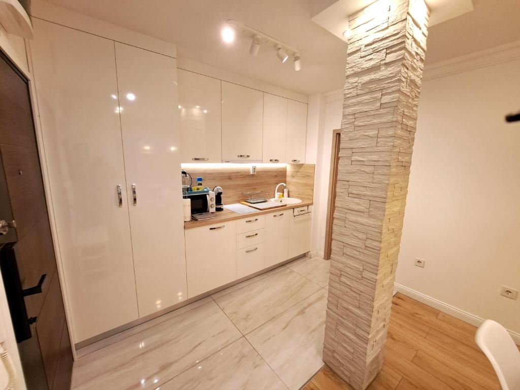 札格雷布的住宿－Zagreb4you Apartments，厨房配有白色橱柜和石柱。