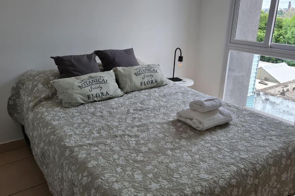 a bed with two pillows and two towels on it at Altos del Rey Apartamentos in San Salvador de Jujuy