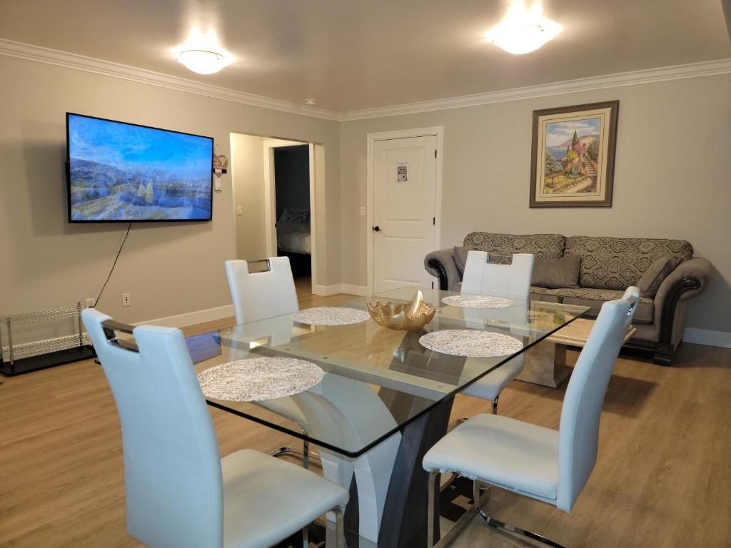 a dining room with a glass table and white chairs at Oscar INN & 2bd Family Suite or Private Room in Abbotsford