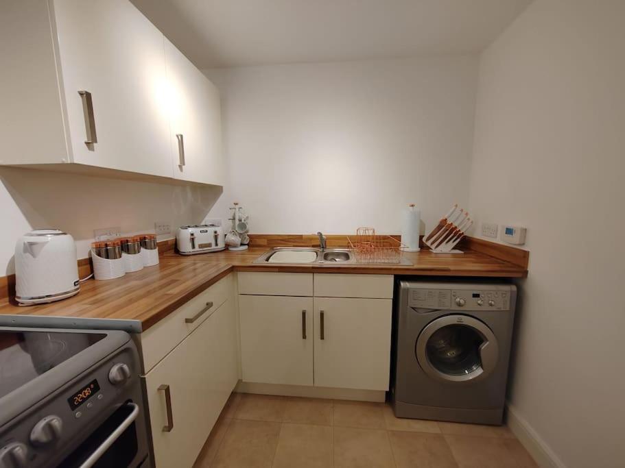 a kitchen with a sink and a washing machine at Modern Huddersfield apartment in Huddersfield