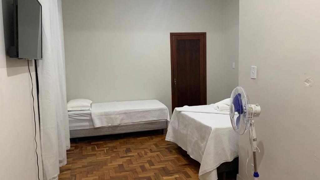 een ziekenhuiskamer met 2 bedden en een ventilator bij HOSTEL ECONOMIC DIVINOPOLIS in Divinópolis