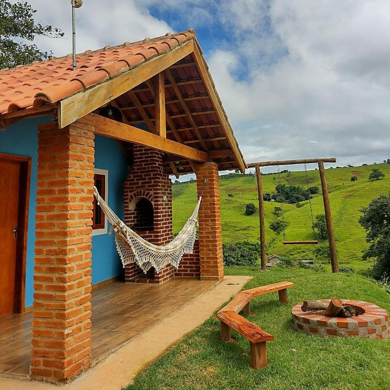 a blue house with a hammock on a deck at Chalés Encantos de Minas in Bueno Brandão